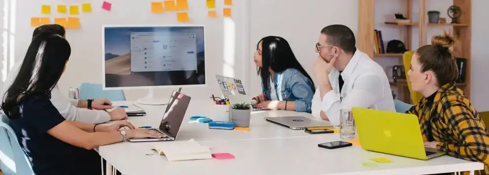 A group working together at a gift, looking at a large white monitor