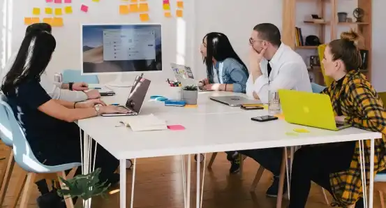 A group working together at a gift, looking at a large white monitor